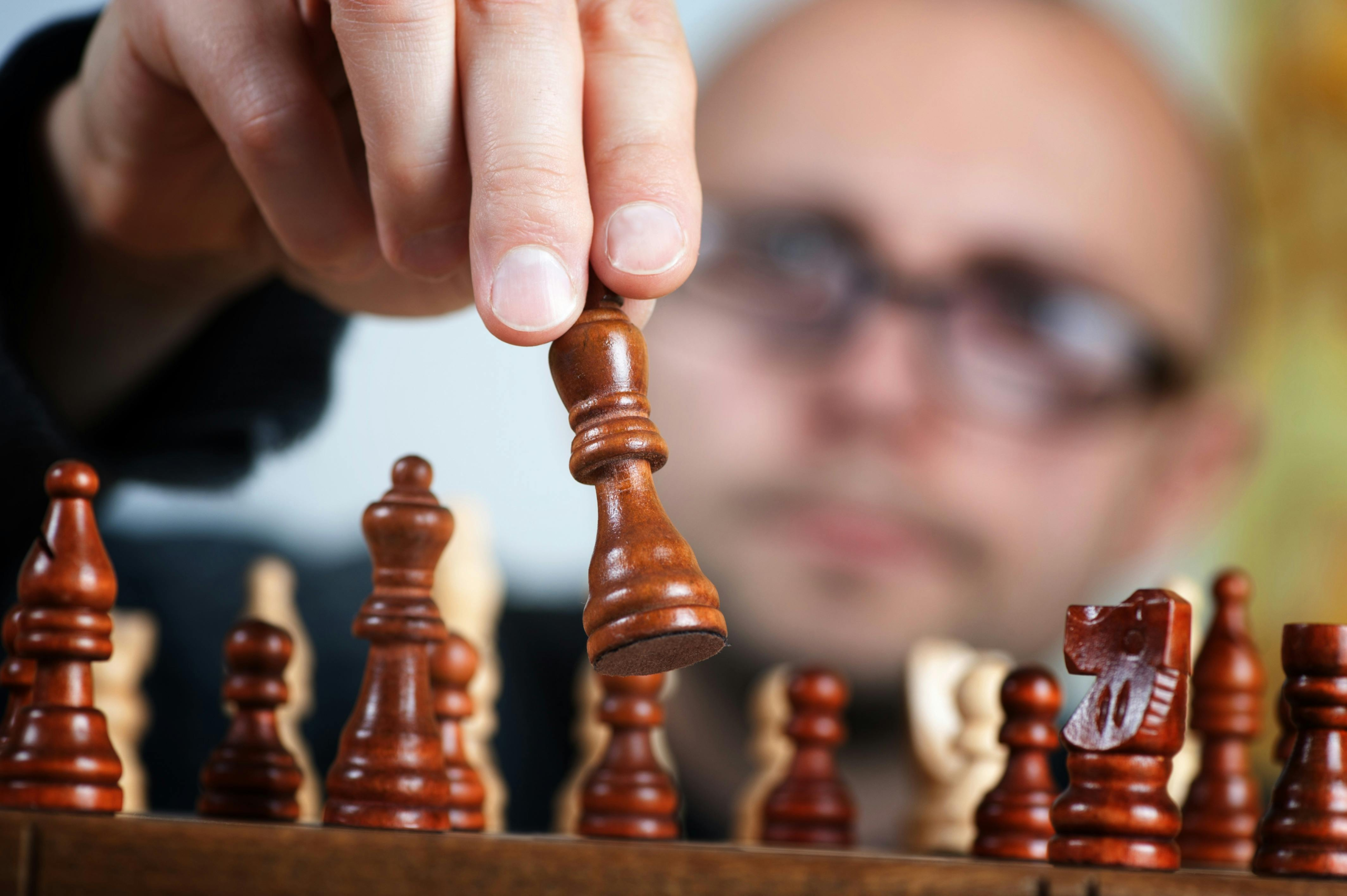 Close-up of a chess player making a strategic move with a focus on the chess piece and the player's intent.